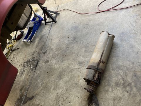 1994 Ford Bronco - Vehicle exhaust pipe removed and resting on the ground next to jack stands.