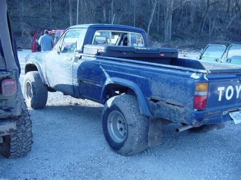 1992 Ford Bronco - A blue pickup truck is parked outdoors with other vehicles nearby.