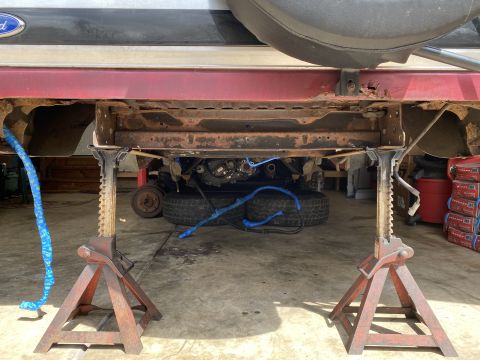 1994 Ford Bronco - Underside view of a vehicle undergoing repairs, with visible rust and suspension parts.