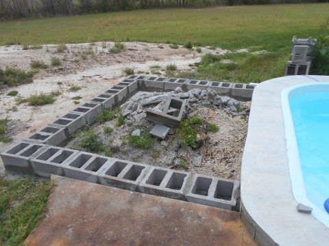 1992 Ford Bronco - A construction scene shows a partially built foundation of cinder blocks next to a bright blue swimming pool.
