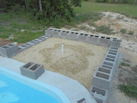 1992 Ford Bronco - A construction site shows cinder blocks being laid out around a gravel-filled area with a pipe, adjacent to a swimming pool.