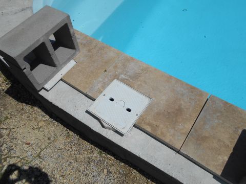1992 Ford Bronco - A cinder block sits on the edge of a swimming pool, near a skimmer access panel.