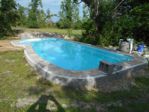 1992 Ford Bronco - An outdoor swimming pool with a concrete deck and surrounding grass is visible, with trees in the background.