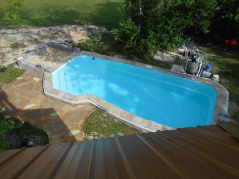 1992 Ford Bronco - A bright blue swimming pool is surrounded by a concrete deck and grassy area, with trees in the background.