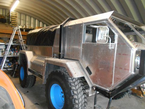 1992 Ford Bronco - This custom vehicle appears to be in a workshop, undergoing construction with exposed metal panels and a canvas covering.