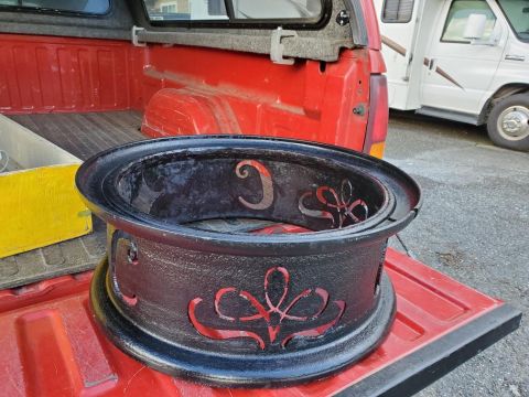 1985 Toyota Hilux - A custom fire pit sits in the bed of a red pickup truck, with an RV visible in the background.