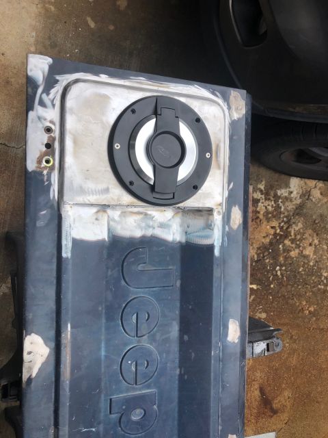 1992 Jeep Wrangler - A Jeep tailgate is shown with a new fuel cap installed, indicating body work in progress.