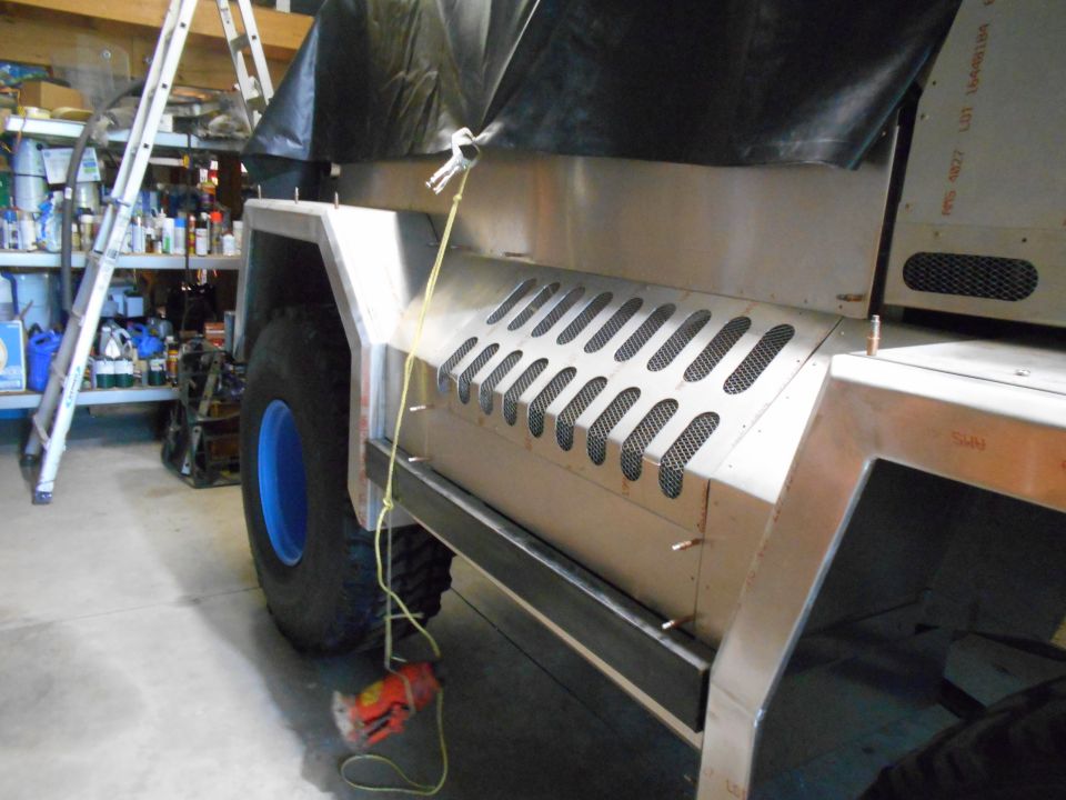 Side panel of custom vehicle with diamond-pattern vents and blue wheel rim