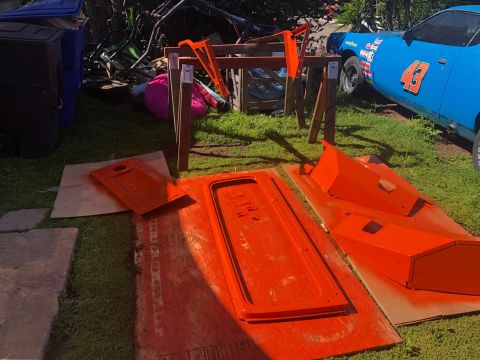 1992 Jeep Wrangler - Car parts painted orange are drying outside near a blue race car with racing decals.