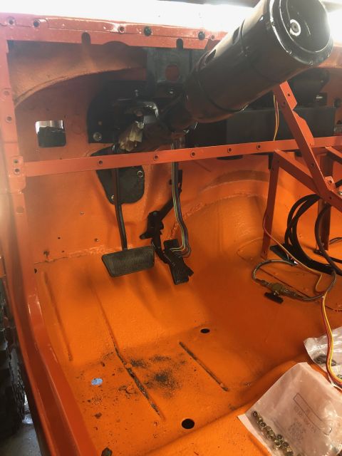 1992 Jeep Wrangler - The interior of an orange Jeep Wrangler is shown during reassembly, with pedals and the steering column visible.
