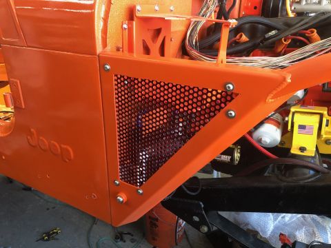 1992 Jeep Wrangler - Close-up of an orange Jeep body panel with a mesh insert, revealing engine wiring and parts.
