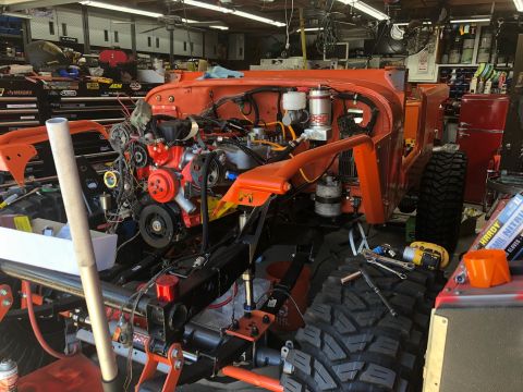 1992 Jeep Wrangler - Orange Jeep Wrangler chassis undergoing reassembly with engine and suspension components visible.
