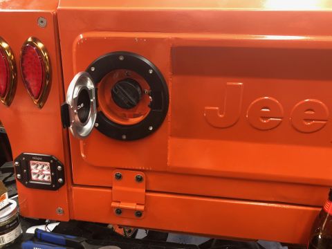 1992 Jeep Wrangler - Close-up of an orange Jeep's rear, an open fuel door and embossed 'Jee' lettering.