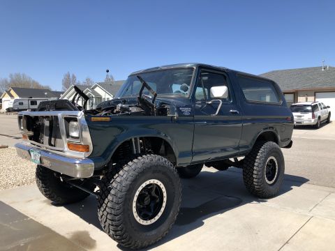 1979 Ford Bronco - This lifted Ford Bronco sits on large off-road tires with its hood open, revealing the engine bay.