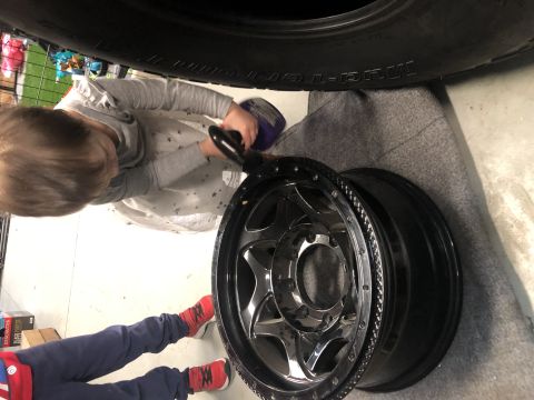 1979 Ford Bronco - A child cleans a shiny chrome wheel, likely part of a vehicle modification project.