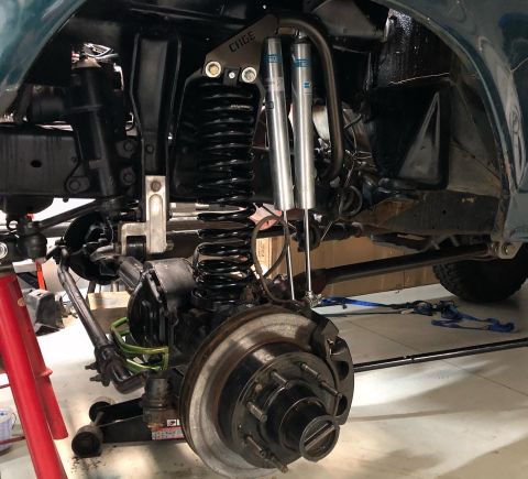 1979 Ford Bronco - Close-up view of a modified vehicle's front suspension system, highlighting custom shock absorbers and coil springs.