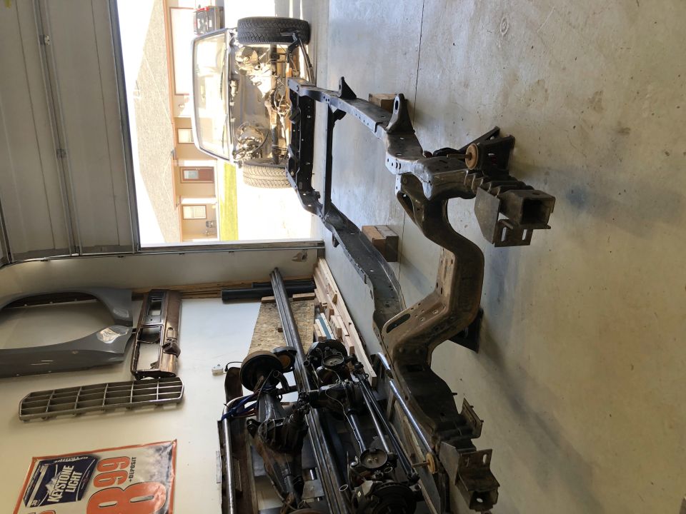 Vehicle frame and assorted parts laid out on a garage floor