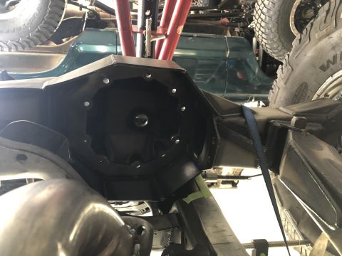 1979 Ford Bronco - The underside of a vehicle shows a heavy-duty differential housing, with other vehicle components and tires in the background.