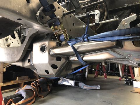 1979 Ford Bronco - Custom suspension components are secured with blue straps on a vehicle frame, suggesting a modification or repair process.