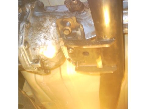 1991 Ford LTD Crown Victoria - Close-up view of a transmission bracket bolted to an exhaust pipe, likely from a vehicle's undercarriage.