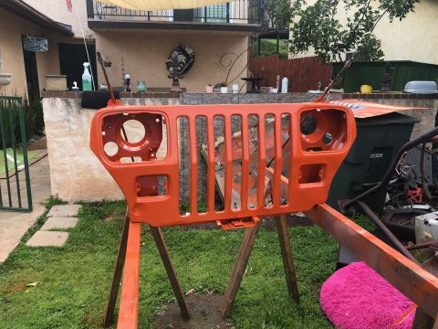 1992 Jeep Wrangler - An orange Jeep Wrangler grille is mounted on sawhorses in a grassy yard, awaiting further work.