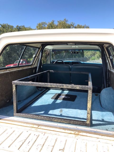 1981 Ford Bronco - Rear view of a white 1978 Ford Bronco showing the interior cargo space with blue carpet and a metal frame.