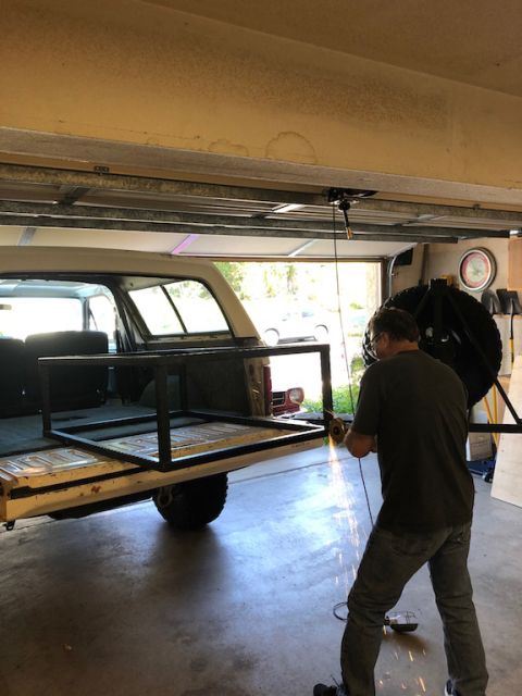 1981 Ford Bronco - A man welds a custom rack onto the tailgate of a 1980 Ford Bronco in a garage.