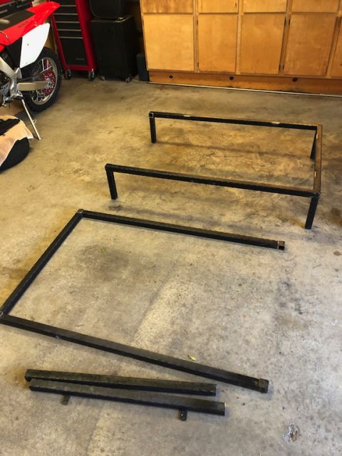 1981 Ford Bronco - Metal frame parts are disassembled on a garage floor next to a motorcycle.