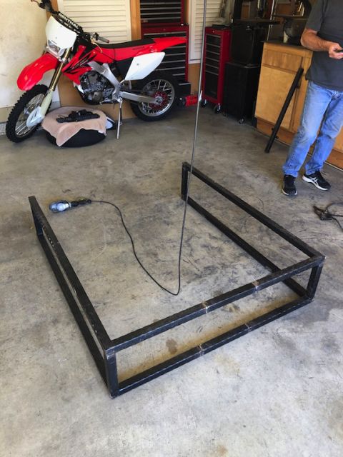 1981 Ford Bronco - A red dirt bike is parked in a garage, with a metal frame project in the foreground.