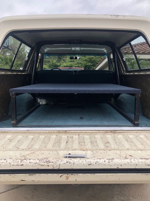 1981 Ford Bronco - Rear view of a 1981 Ford Bronco's interior, showing a custom-built bed platform over the rear cargo area.