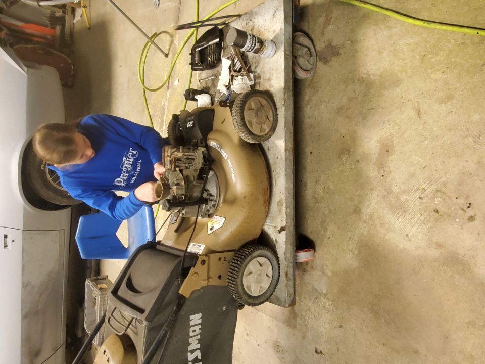 Guy in blue sweatshirt fixing a Craftsman lawnmower engine on a metal table