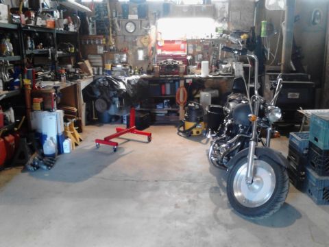 1978 Ford Bronco - A motorcycle sits in a garage filled with tools, car parts, and a shop vac.