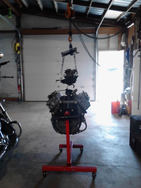 1978 Ford Bronco - Engine assembly being worked on in a garage, suspended by a hoist and on an engine stand.