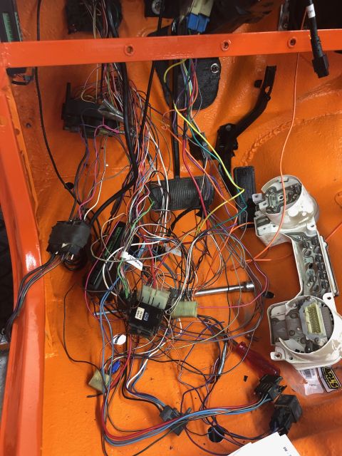 1992 Jeep Wrangler - A complex wiring harness is visible inside an orange vehicle, with a disconnected instrument cluster to the right.