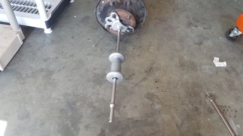 1985 Ford Bronco - A slide hammer is connected to a wheel hub assembly, likely for removal or installation.