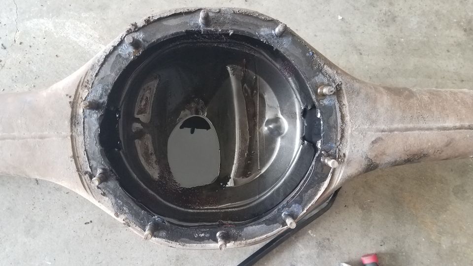 Open differential housing with some oil inside. It looks like the cover has been removed