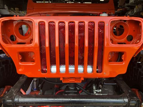 1992 Jeep Wrangler - Front view of an orange Jeep Wrangler undergoing reassembly, showing its distinctive grille.