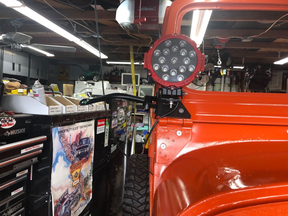 Orange Jeep Wrangler side view, showing a large red LED light mounted on the roll cage and a Supermotors.net logo