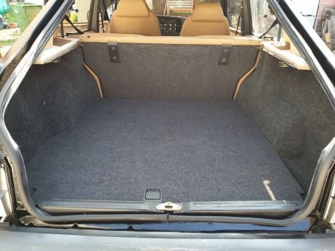 1991 Saab 900 - The carpeted trunk of a car is shown, with the rear seats visible through the open hatch.