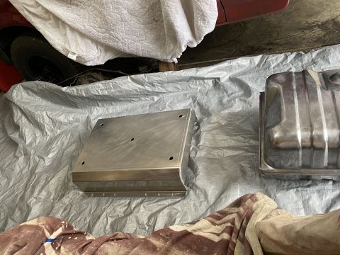 1994 Ford Bronco - Two automotive parts, a fuel tank and skid plate, are laid out on a tarp.