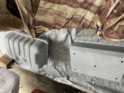 1994 Ford Bronco - Two automotive parts, a fuel tank and a skid plate, are laid out on a tarp.