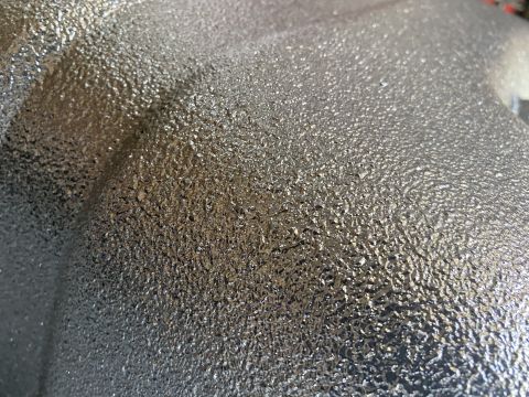 1994 Ford Bronco - A close-up view of a textured metal component, possibly from a vehicle's undercarriage or exhaust system.