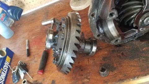 1985 Ford Bronco - Differential gears and housing disassembled on a wooden surface, with tools nearby.