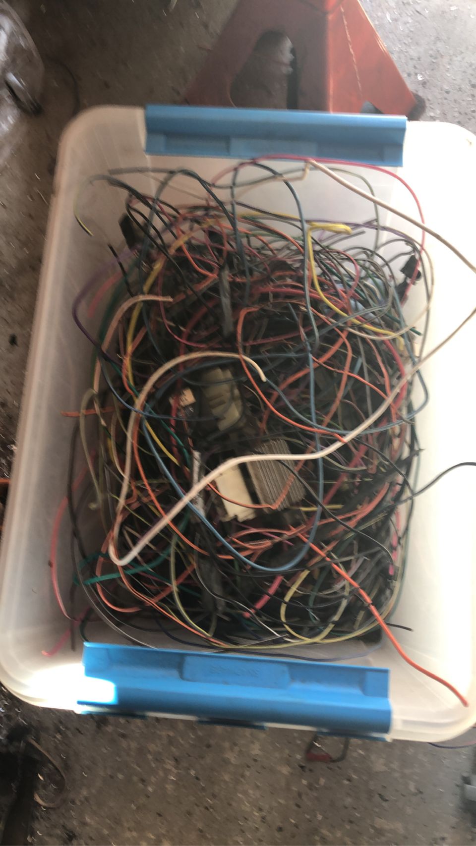 Tangled wires in a clear plastic bin with blue trim