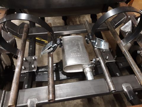 1985 Toyota Hilux - The underside of a vehicle shows a new muffler being installed with various metal components and strap components.