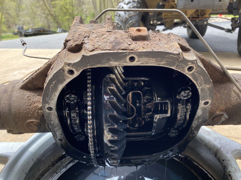 Open differential housing showing gears and chain, with oil dripping into a pan below