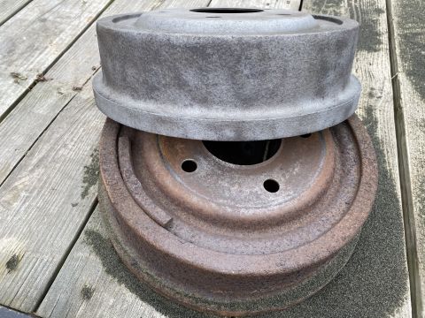 1994 Ford Bronco - Two drum brake assemblies are shown stacked on a weathered wooden surface.