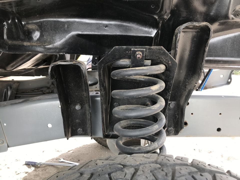 Close-up of a vehicle's front suspension coil spring and mounting bracket