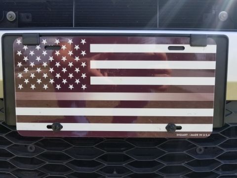 2017 Ford Explorer - License plate a stylized American flag design is mounted on the front grille of a vehicle.