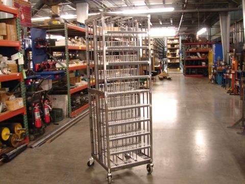 1973 Ford Ranchero - A metal shelving cart with multiple tiers stands in a warehouse aisle, surrounded by storage racks.